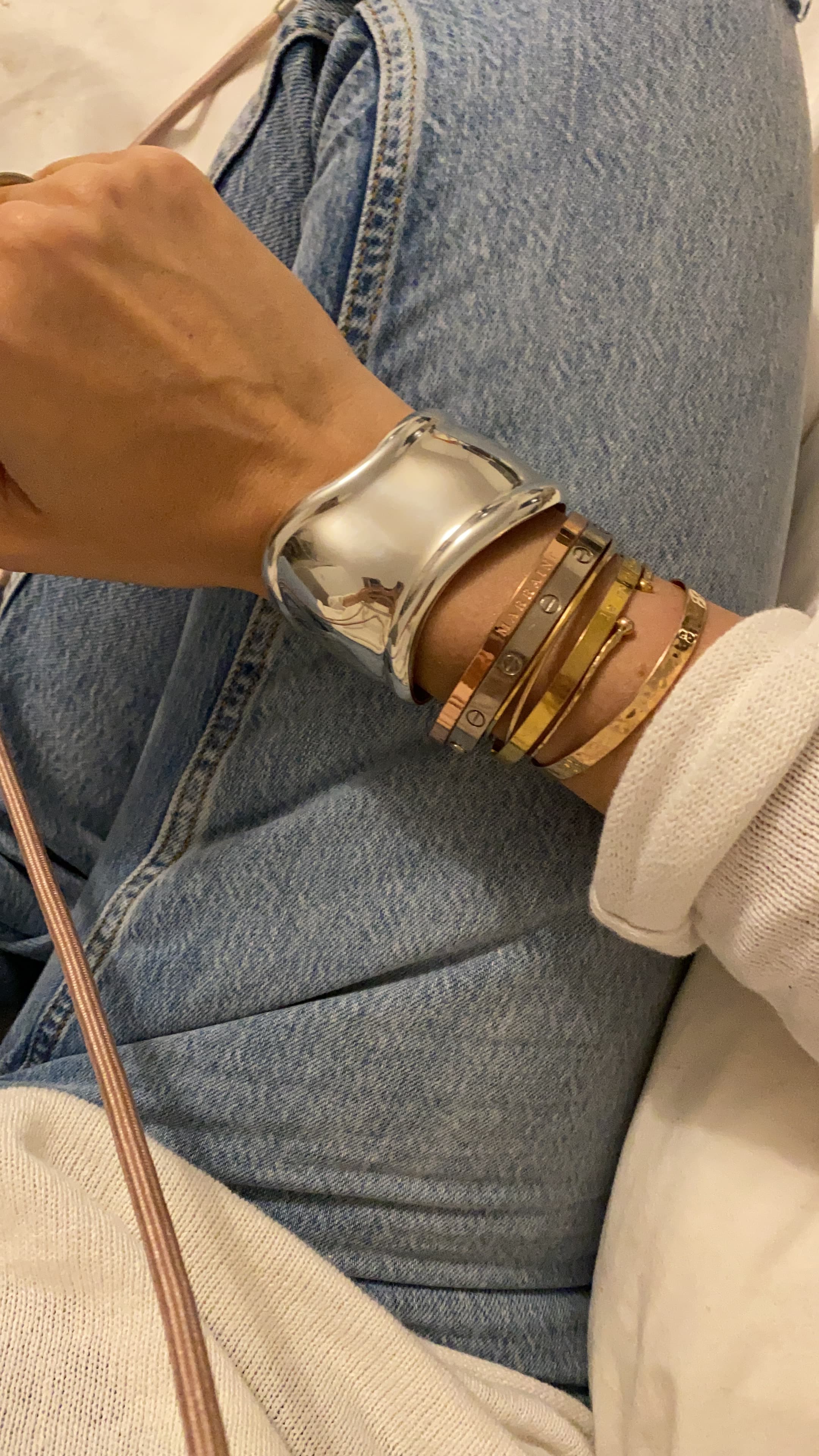 Manchette dorée portée au poignet, empilée avec d'autres bracelets